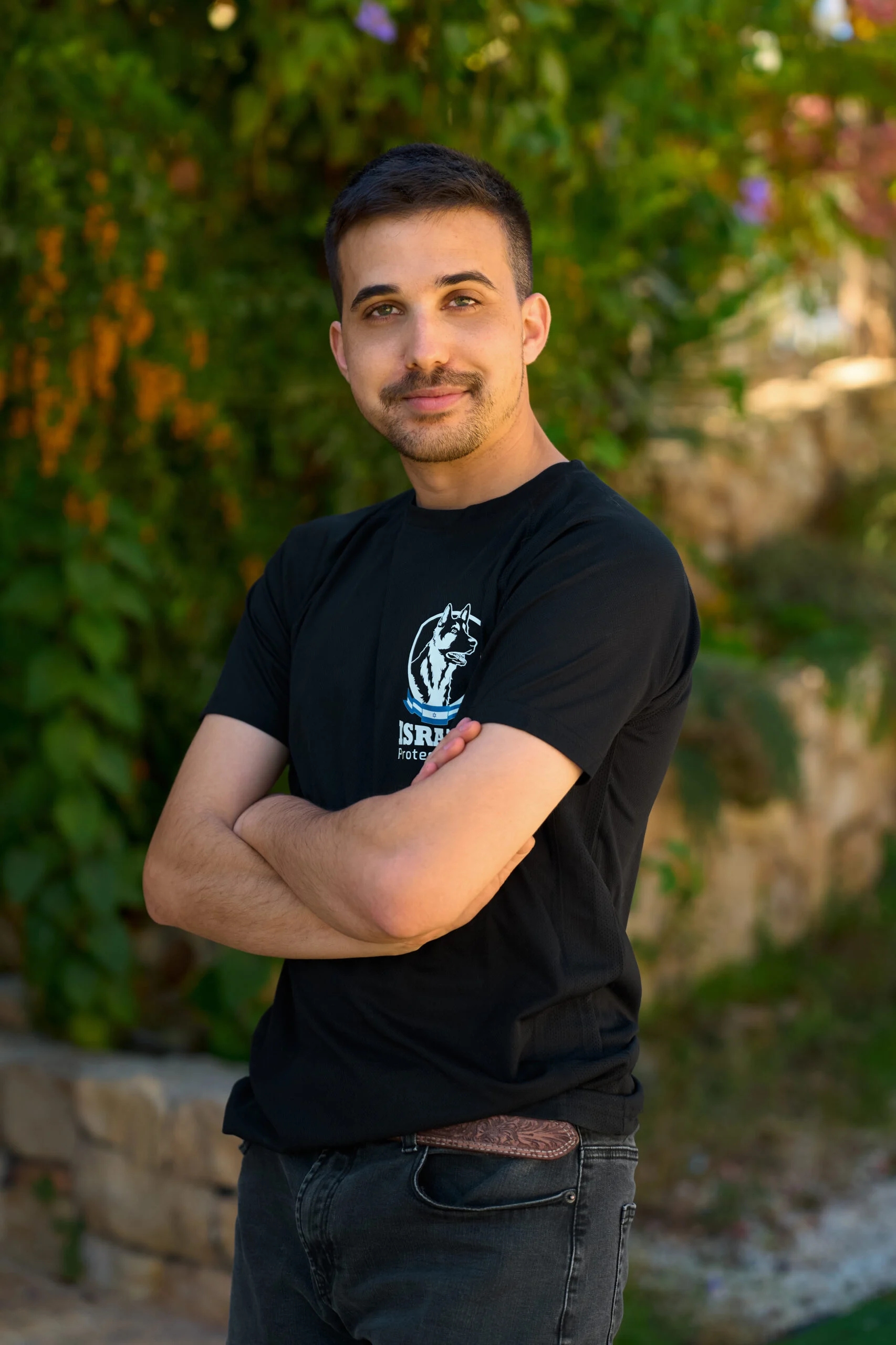 Erez, Israel Protection K9 trainer, standing confidently with crossed arms.